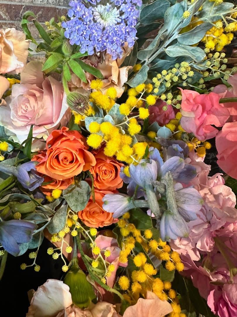Mixed bouquet with orange and pink roses, blue flowers, and yellow filler blooms