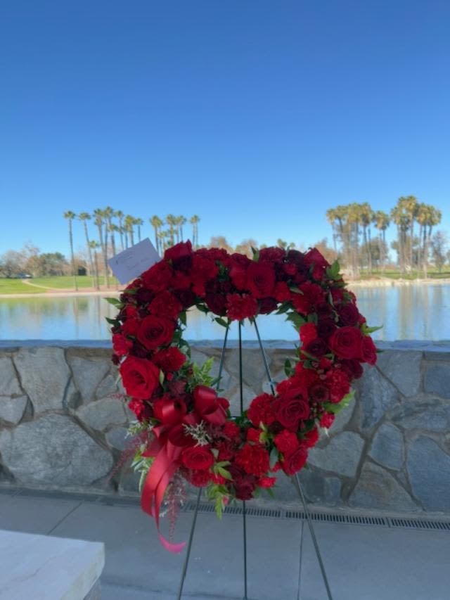 With Love, Always - This all red heart is lush and dramatic and absolutely stunning. It's designed full of red roses, carnations, minis, sprays, and soft dark greenery to set off the beautiful red blooms. Standard picture shown is created on a base wreath of 18" Deluxe and Premium price points will be upgraded in size, while keeping the same types of flowers shown. 