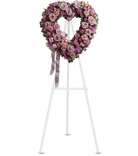 Heart-shaped pink rose wreath on a white easel with ribbon