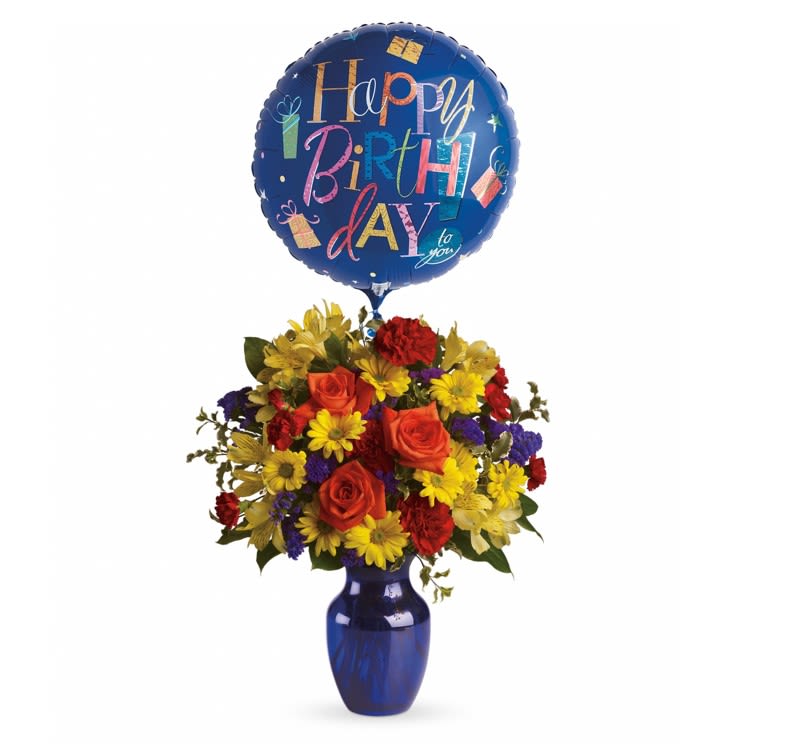 Fly Away Birthday Bouquet - A round balloon floats above a compact, colorful birthday bouquet that feels like a celebration in bloom - a perfect birthday or "just because" gift that instantly lifts someone's spirits. This flower arrangement combines bright red, yellow, orange and purple tones for a lively, festive look that suits both men and women and works equally well for birthdays, congratulations, or to surprise the person you're thinking of.  The mix includes brilliant orange roses, yellow alstroemeria, red carnations (with miniature carnations), yellow daisy spray chrysanthemums and purple statice arranged in a dense, rounded shape inside a striking blue glass vase. The presentation is medium-height and gift-ready, with a full, cheerful profile and a matching mylar birthday balloon for extra flair. Dimensions are approximately 16 3/4" W x 19 1/4" H; simple care-fresh water and a cool spot-keeps the blooms looking their best so your recipient feels celebrated long after the surprise.