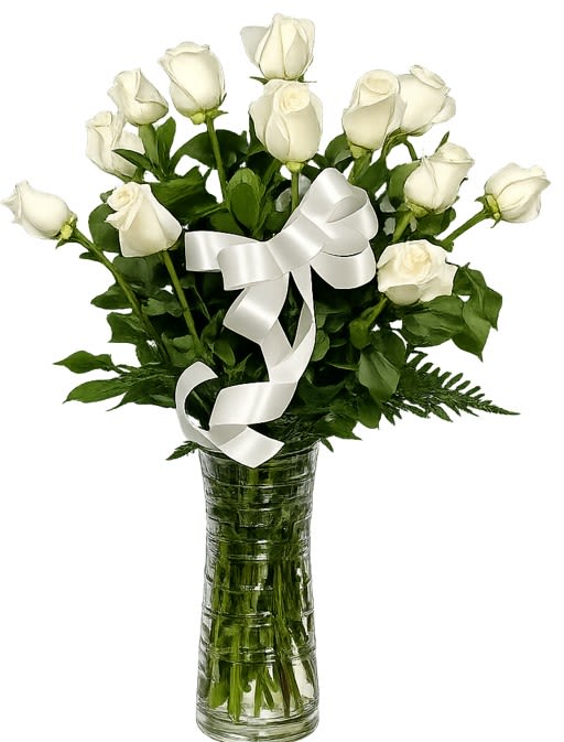 Classic Dozen of White Roses - A cluster of twelve white roses arranged with clean, formal lines makes a quietly powerful sympathy arrangement that also suits weddings, anniversaries, or a simple gesture of caring. The Classic Dozen of White Roses presents open blooms at varying stages so the person you're honoring will see soft layers of petals and a gentle, living texture that reads as both peaceful and refined.  Set in a tall clear glass vase and finished with a large white satin ribbon, the arrangement pairs luminous white petals with dense green foliage for a restrained, elegant silhouette. The vase height gives presence on a memorial table or entry console; stems are trimmed to proportion so the roses sit tightly together and maintain their composed shape.  For someone grieving or marking a solemn milestone, these roses convey purity and steady comfort; for a bride or anniversary recipient, they read as timeless and sincere. Roses arrive ready to display-refresh water every 2-3 days, recut stems at an angle if possible, and keep away from direct heat to prolong bloom life.