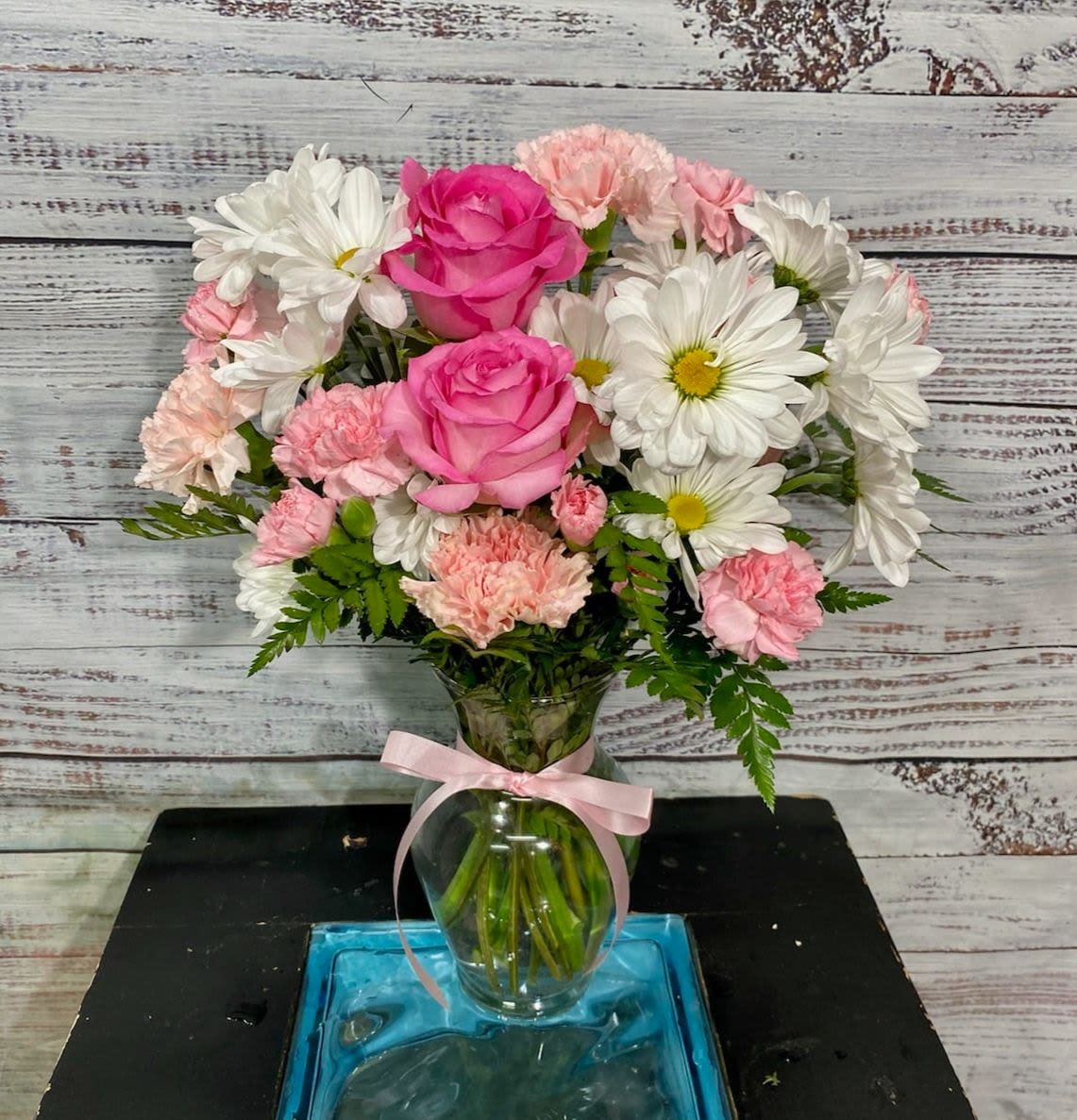 Pink Promises - Your loved one will be tickled pink when they get this arrangement.  Roses, carnations, and daisies in hues of pink are hand arranged in a clear recycled glass vase.  A great arrangement for breast cancer awareness, baby showers, or whatever occasion.   Approximately 12" tall. 