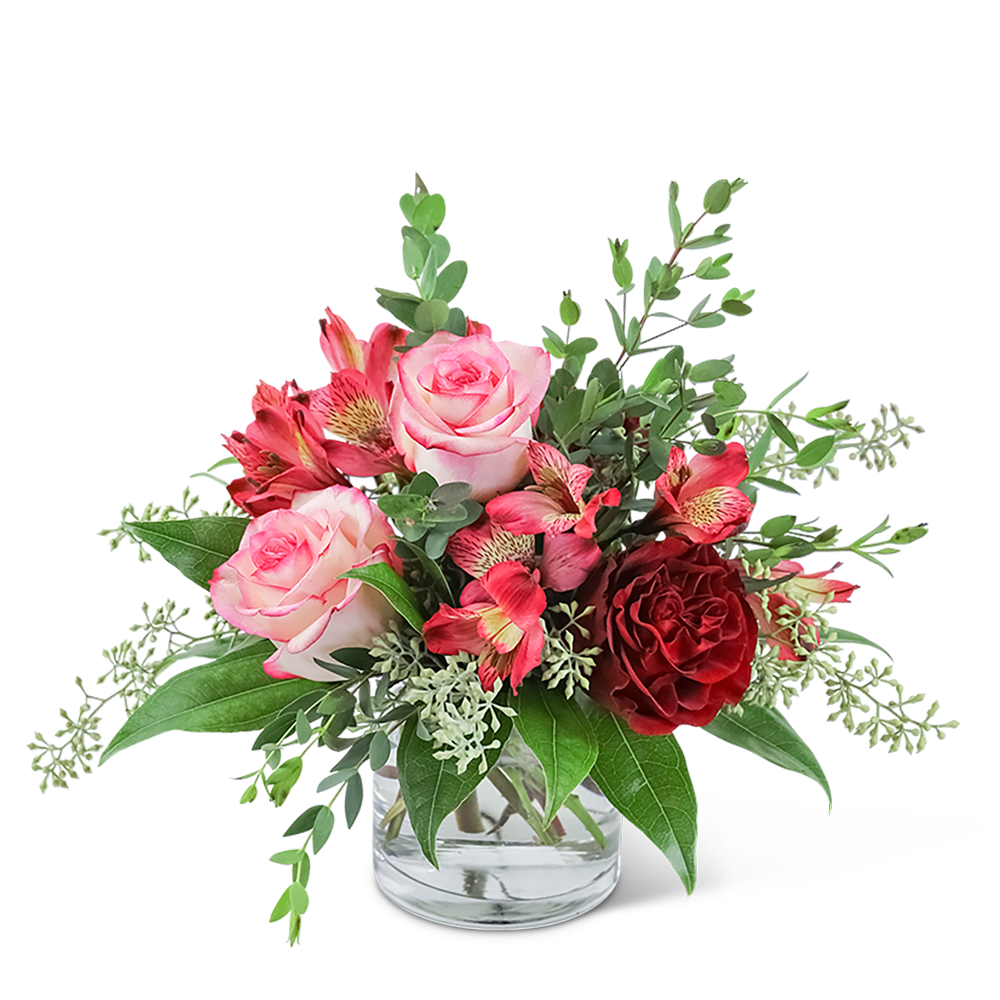 Pink and red roses in a clear glass vase with greenery