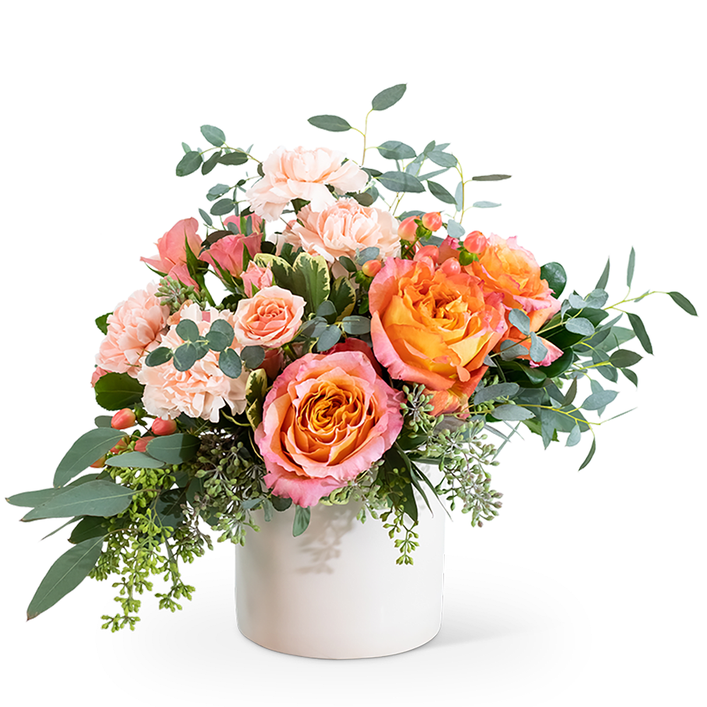 Peach and pink roses with pale carnations in a white vase