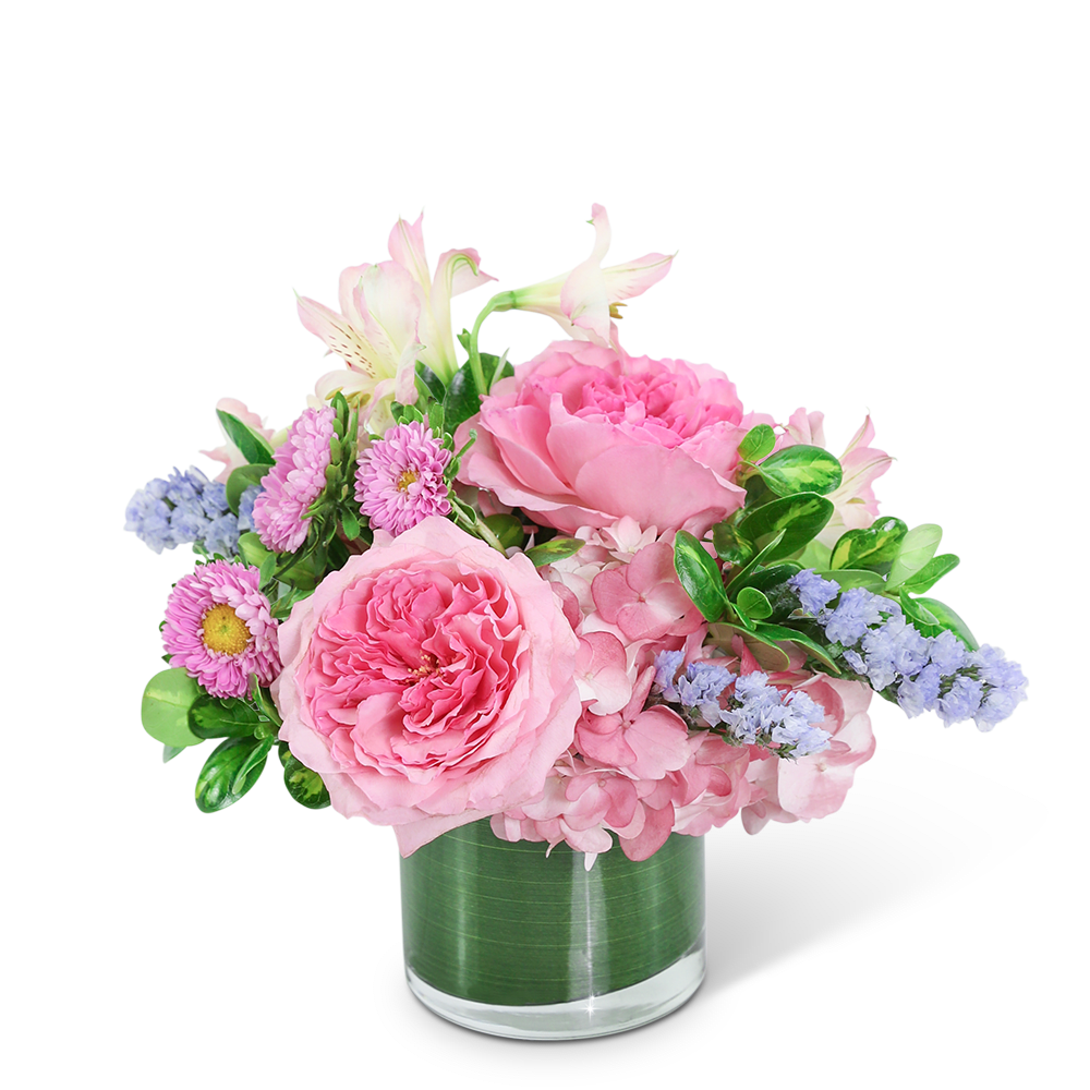 Pink floral arrangement in a clear glass vase with lavender accents