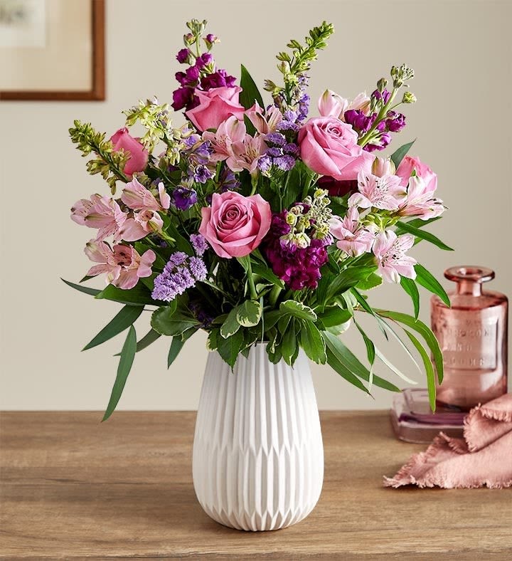 Lavender Elegance - Send a sweet, thoughtful expression with our everyday bouquet. Hand designed by our florists, this garden-inspired gathering features soothing lavender and purple, along with accents of cascading greenery. It’s arranged in our keepsake White Modern Vase, with a tapered design and matte finish that complements the beauty of every bloom.  All-around arrangement with lavender roses, Peruvian lilies (alstroemeria) and statice, purple larkspur and stock; accented with feather willow eucalyptus and assorted greenery Artistically designed in our Modern White Vase, with a tapered design and a matte finish, for a contemporary look that also has a softness to it, to complement everyday arrangements; measures 8"H x 5.35"L x 5.35"W  Our florists select the freshest flowers available, so colors and varieties may vary due to local availability To ensure lasting beauty, Peruvian lilies may arrive in bud form and will fully bloom over the next few days