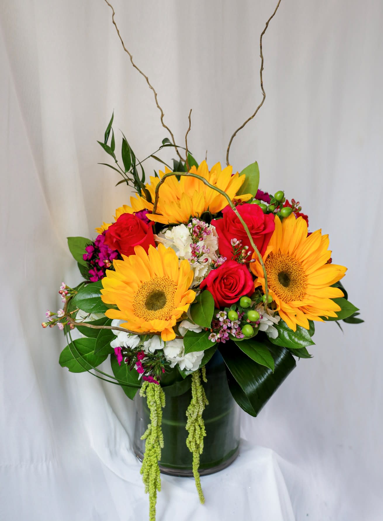 Bright bouquet of sunflowers and red roses in a glass vase