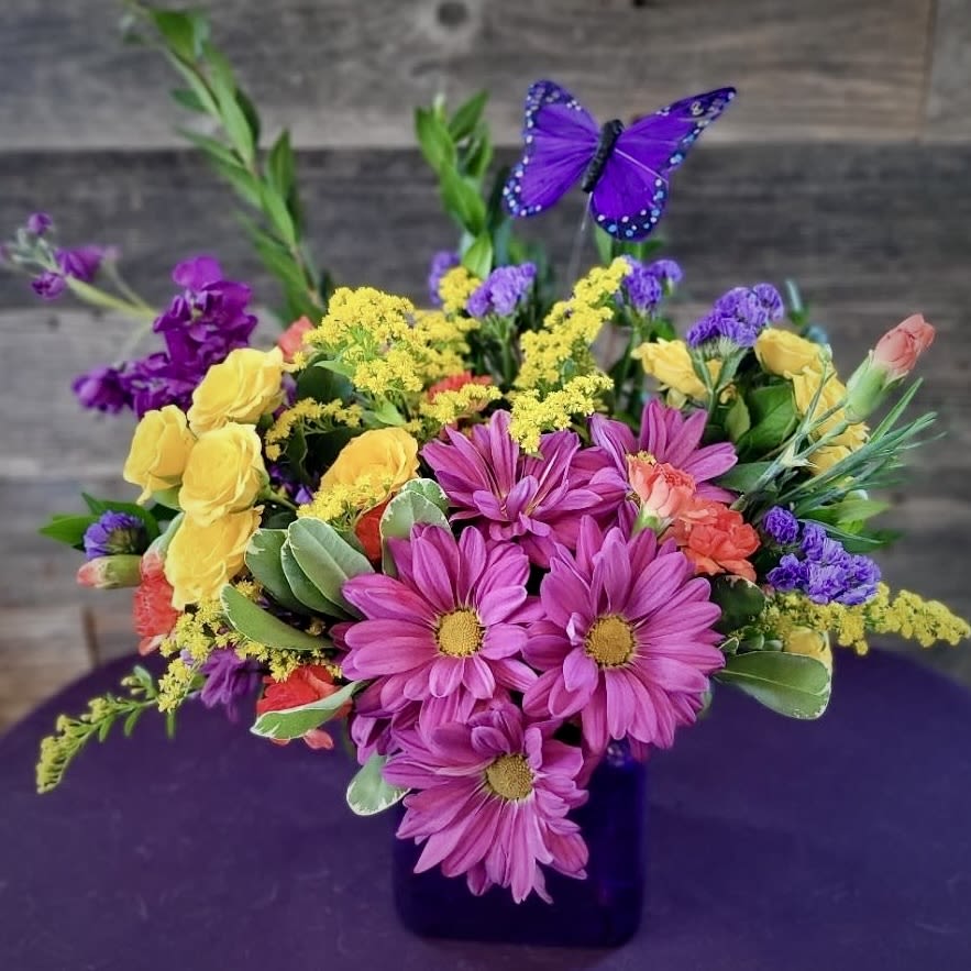 Colorful bouquet in a dark vase with purple daisies and yellow roses