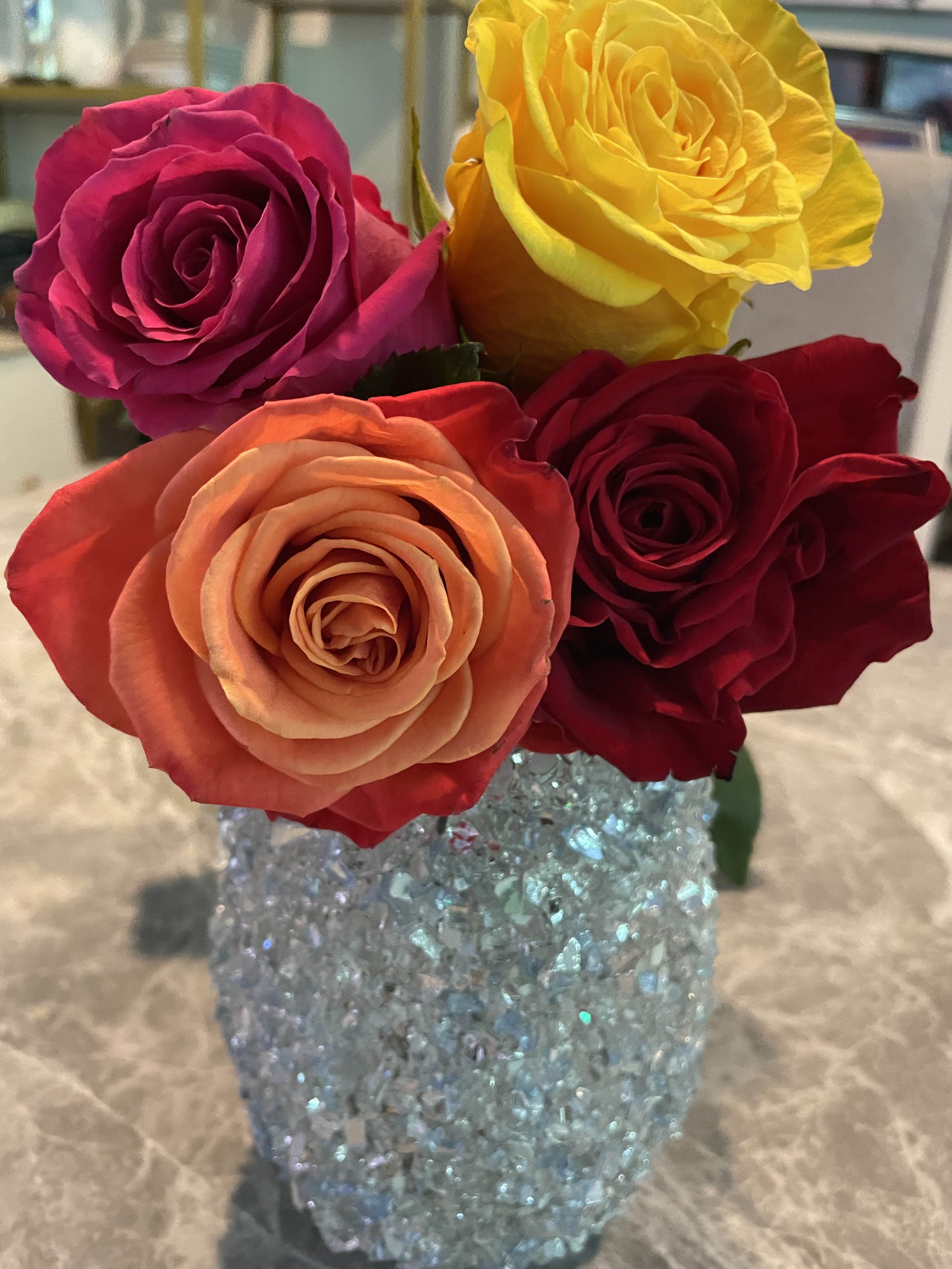 Four roses in a glittery blue vase