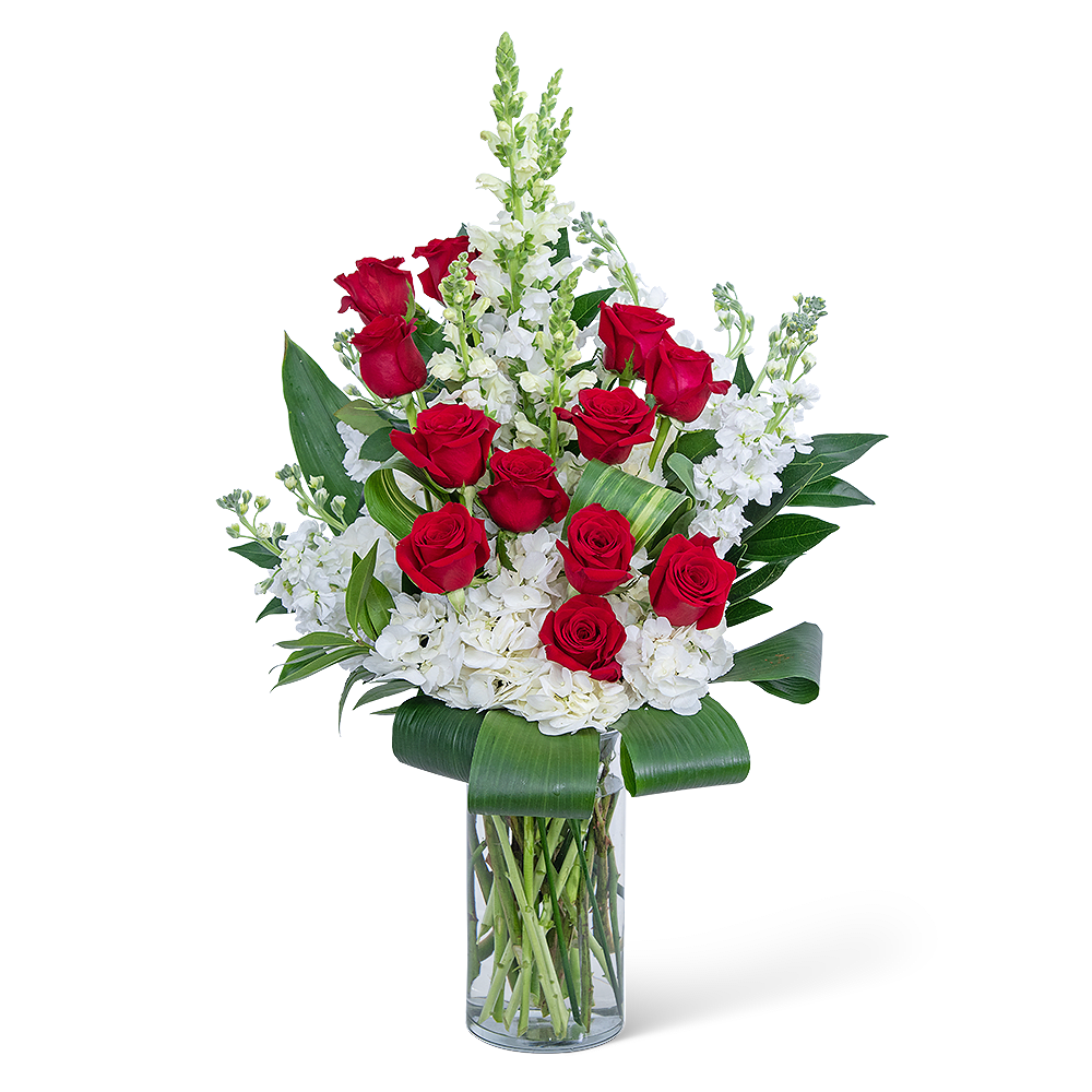 Red roses and white flowers arranged in a clear glass vase