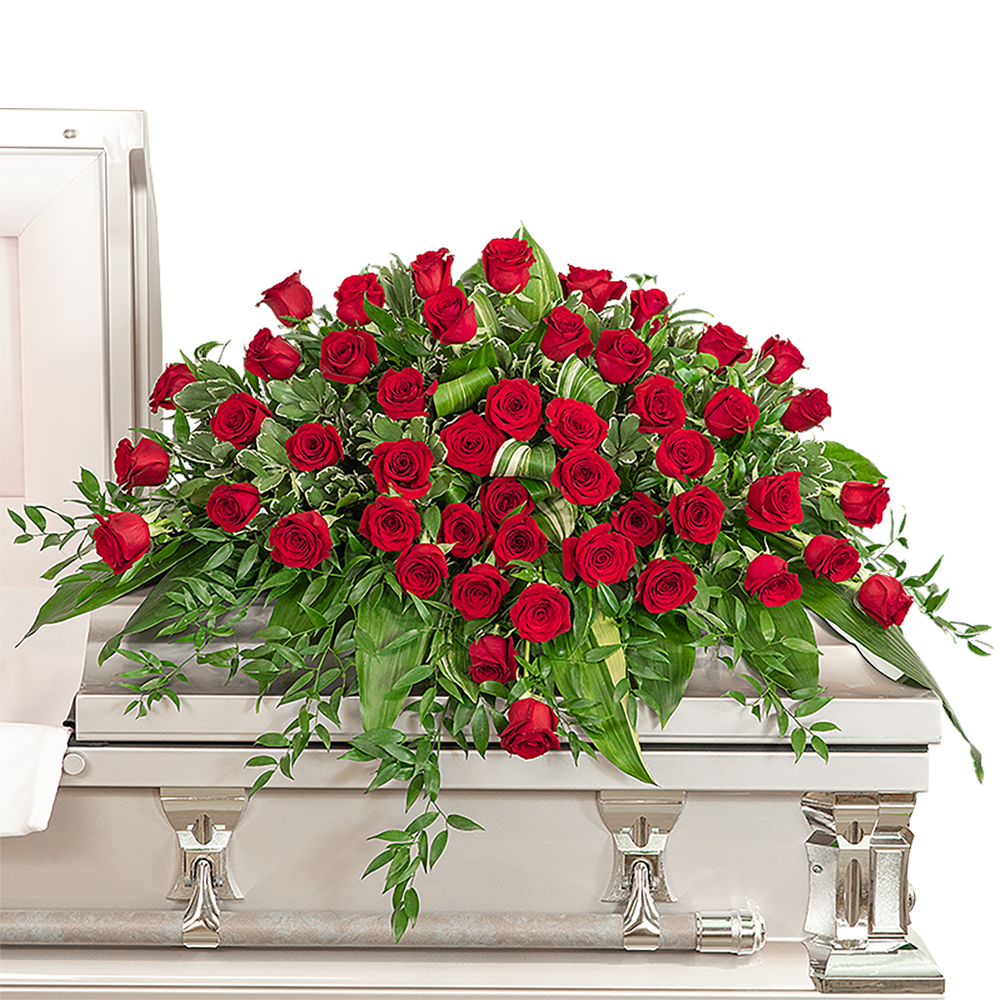 Red rose casket spray with trailing greenery on a white coffin
