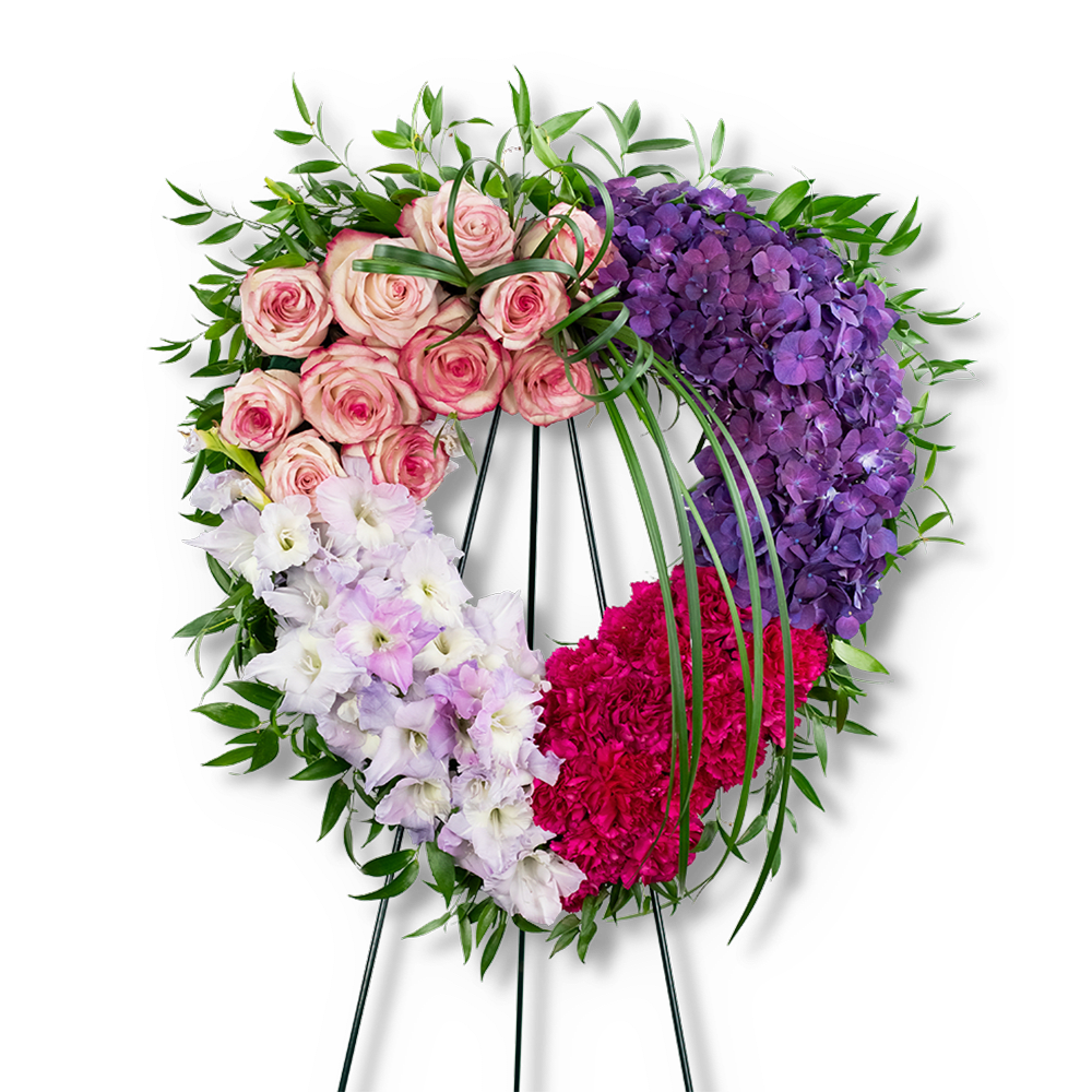 Heart-shaped floral wreath with pink roses, purple hydrangeas, white flowers, and magenta carnations
