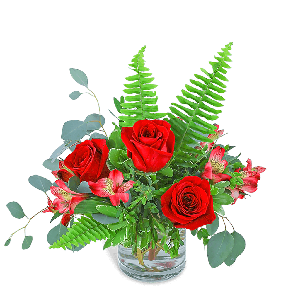 Red roses and pink flowers in a clear glass vase