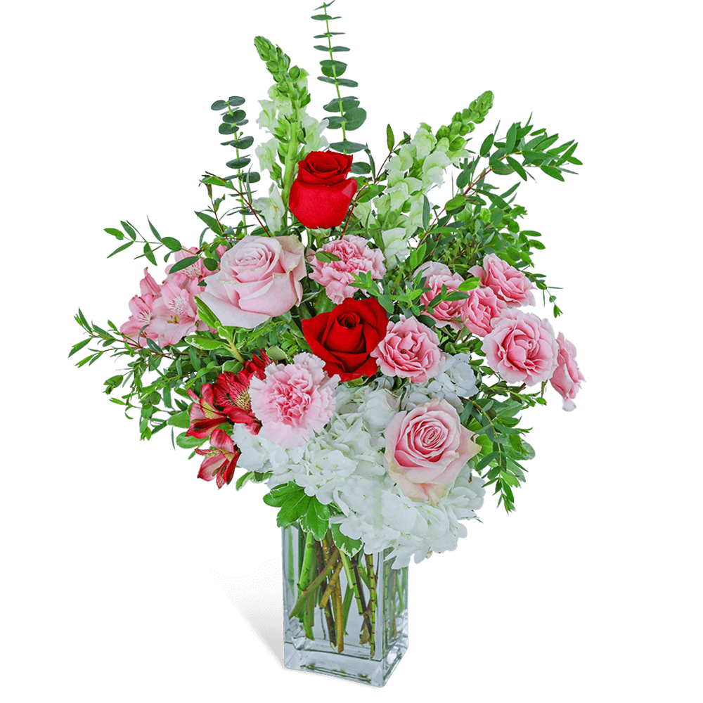 Pink and red roses with white blooms in a clear square vase