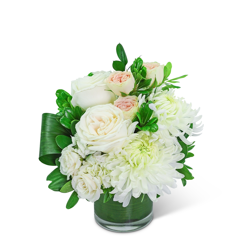 White roses and chrysanthemums in a glass vase with green leaves