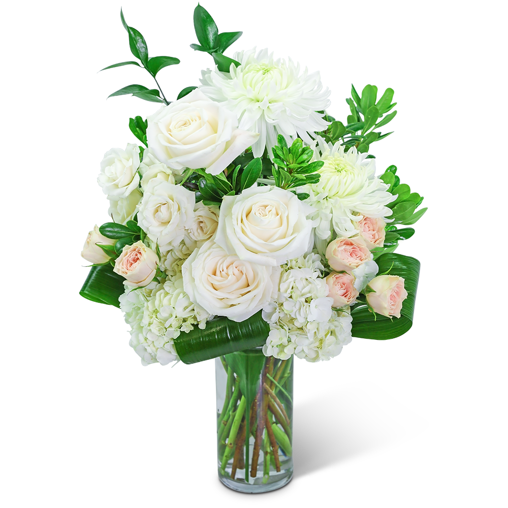 White roses and chrysanthemums in a clear glass vase with green foliage