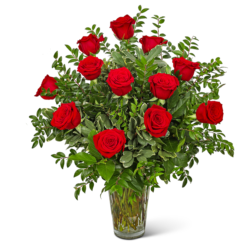 Red roses arranged in a clear glass vase with mixed greenery