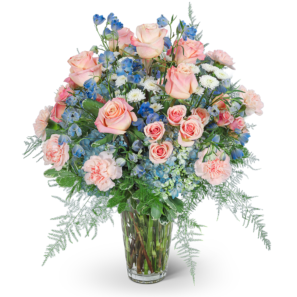 Pink roses, blue flowers, and white blooms in a clear glass vase