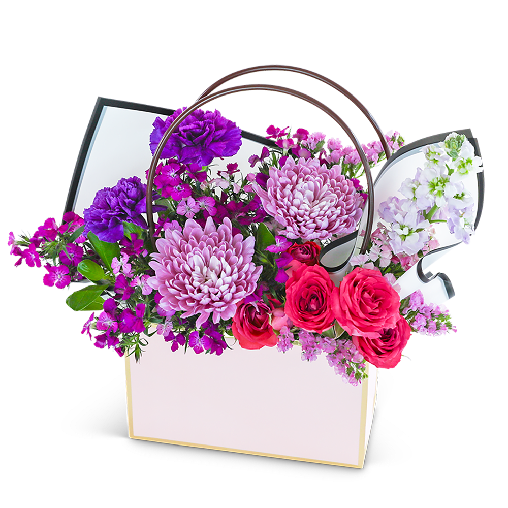 Mixed pink and purple flowers in a white gift bag with handles