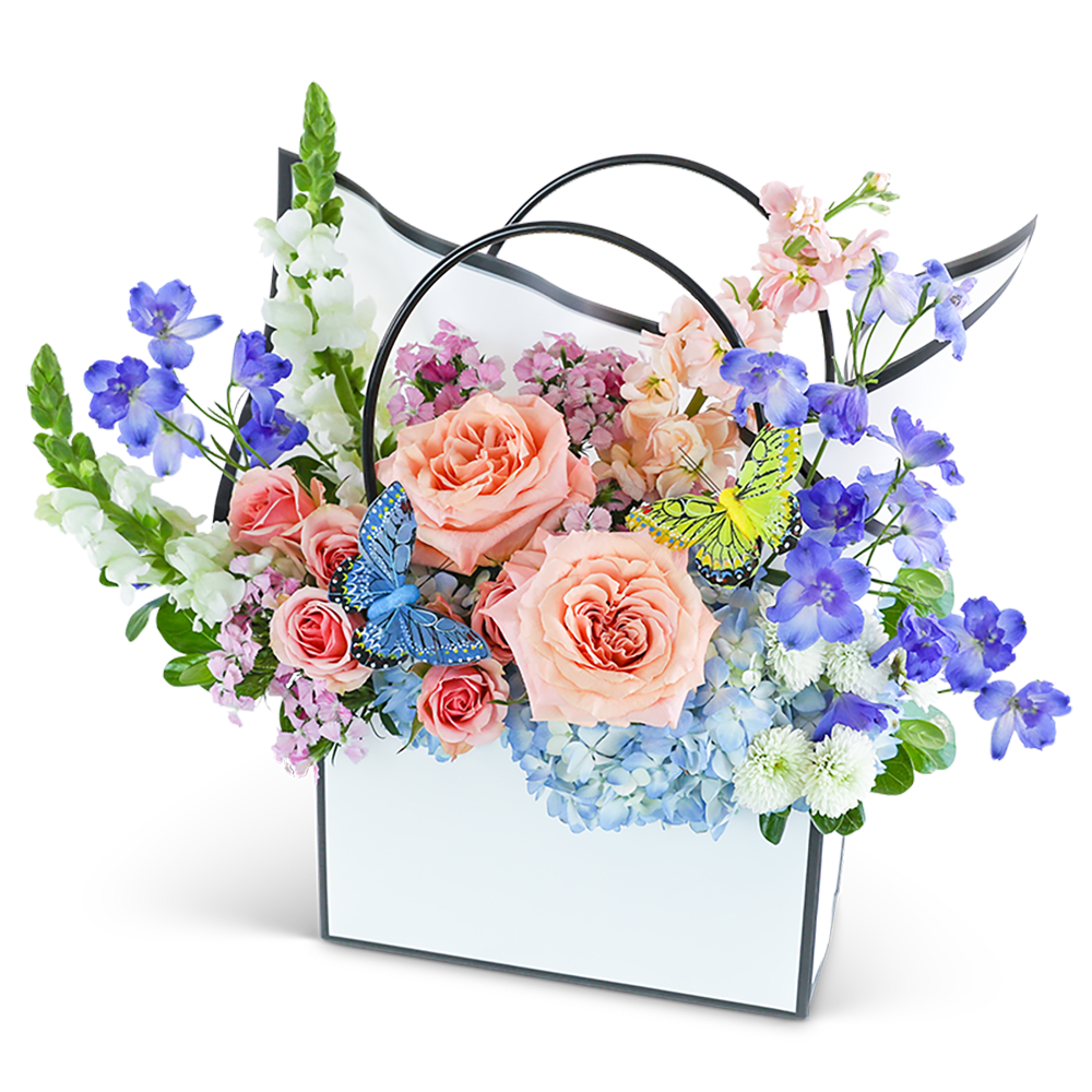Pastel flower arrangement in a white handled box with butterfly accents