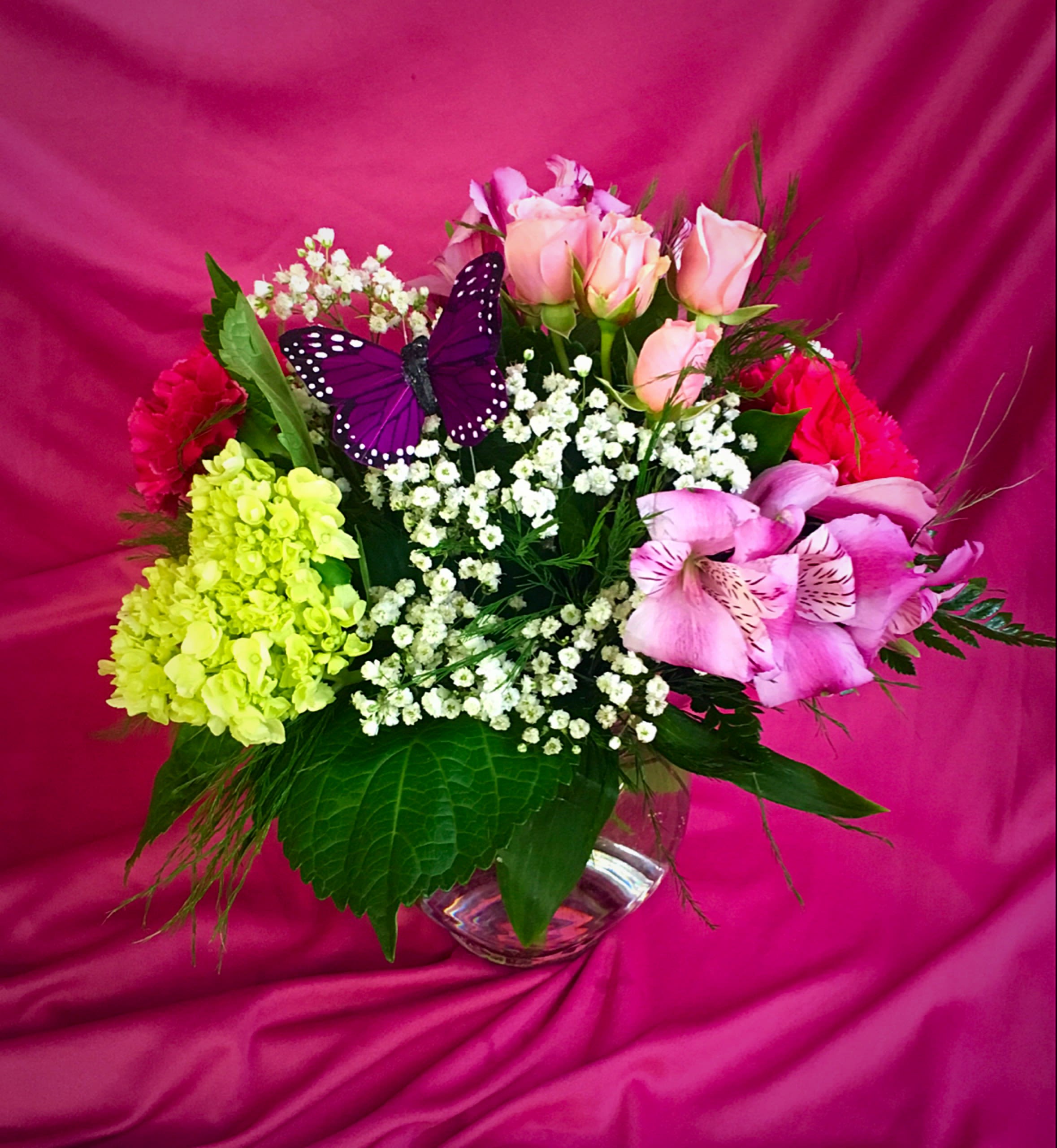 Mixed bouquet of pink roses, lilies, and baby’s breath in a glass vase