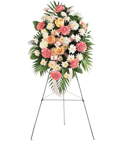 Standing floral spray with pink carnations, peach roses, and white daisies on an easel