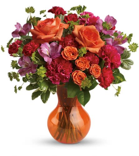 Orange and red mixed bouquet in an amber glass vase