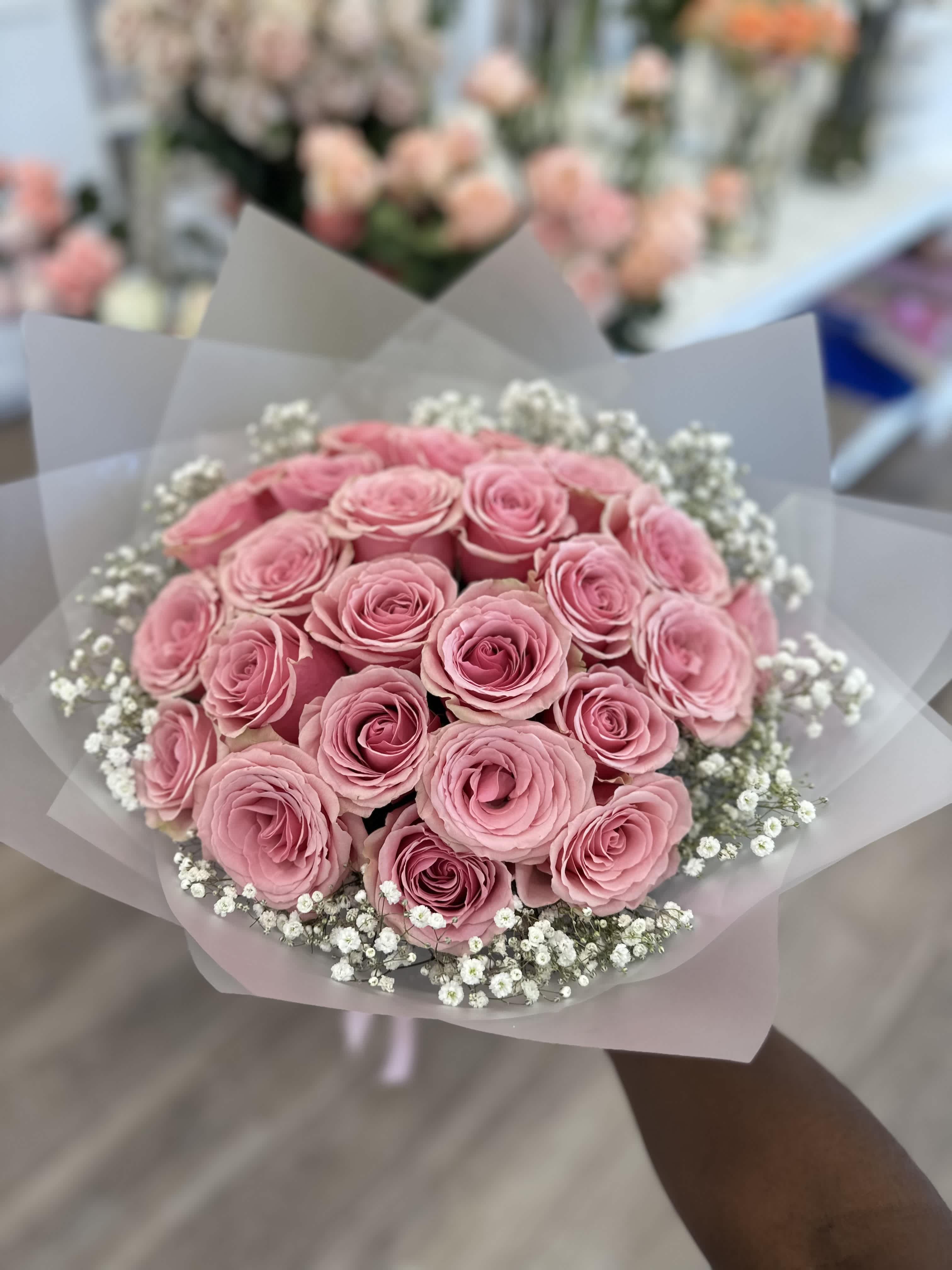 Bouquet of pink roses with white baby's breath in translucent wrap