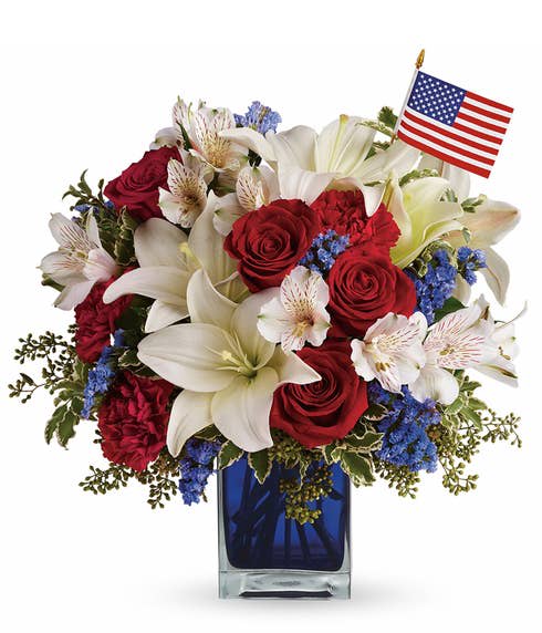 Red roses and white lilies in a blue vase with a small American flag