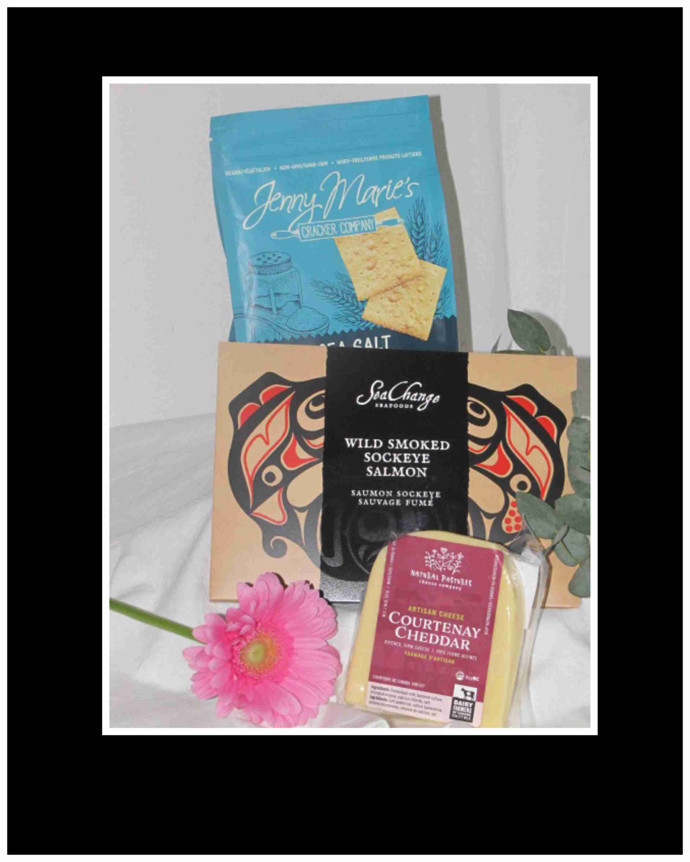 Gift basket with crackers, smoked salmon, cheese, and a pink gerbera daisy