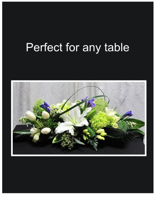 Low floral centerpiece with white lilies, tulips, and purple blooms