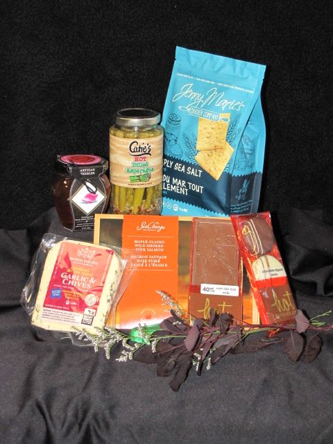 Gift basket with assorted packaged snacks and a jar of pickles