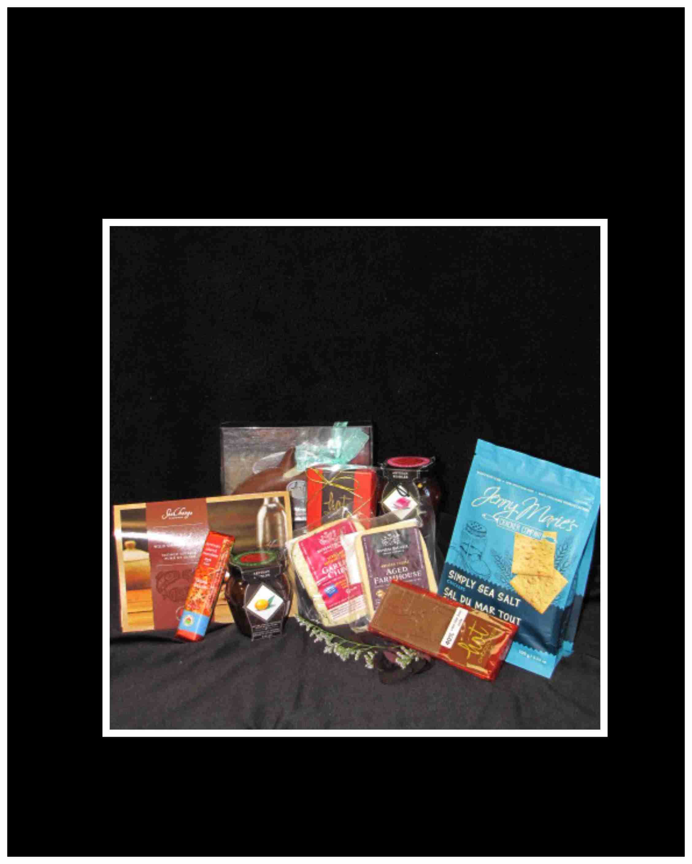 Assorted chocolate and snack gift items arranged on black fabric