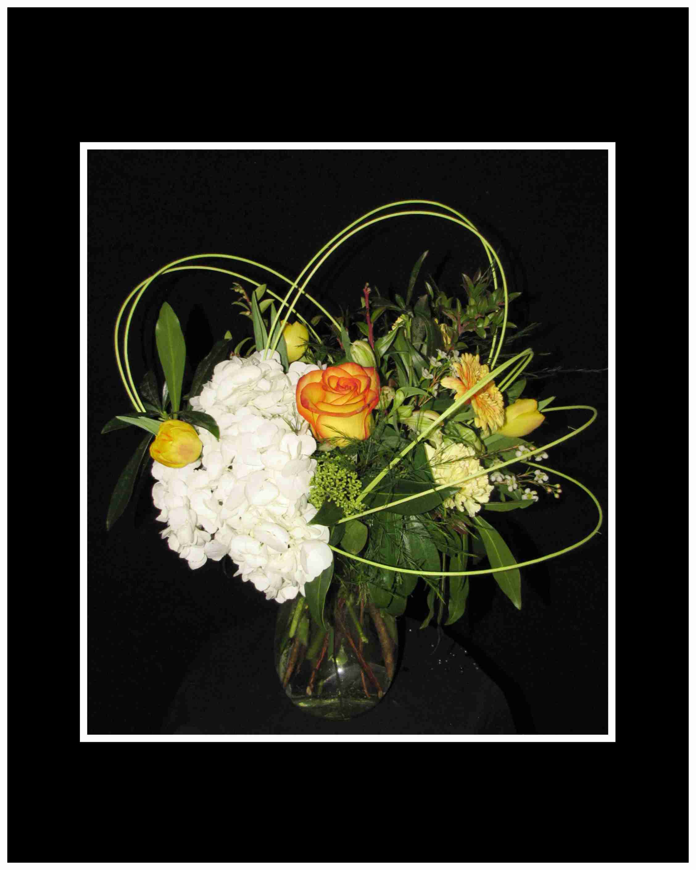 Bouquet of white hydrangeas and orange-yellow roses in a glass vase