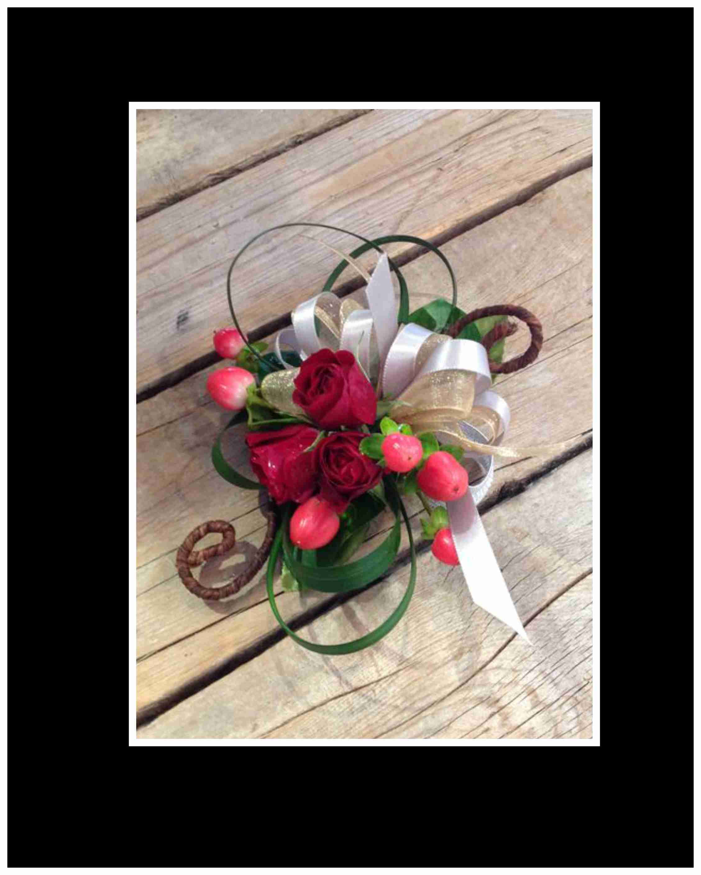 Small bouquet of red roses with ribbon loops and pink berries