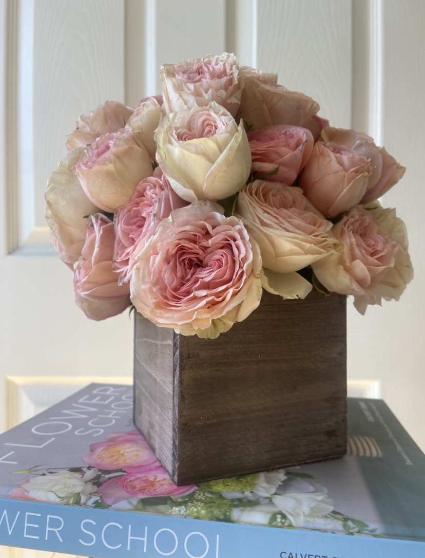 Pink and cream roses arranged in a wooden box