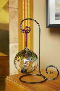 Decorative metal stand holding a colorful glass orb