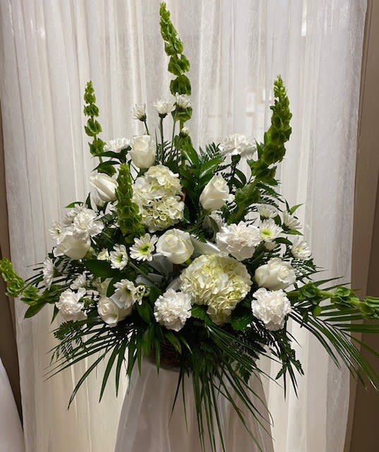 Tall white floral arrangement with roses, hydrangeas, and green spikes