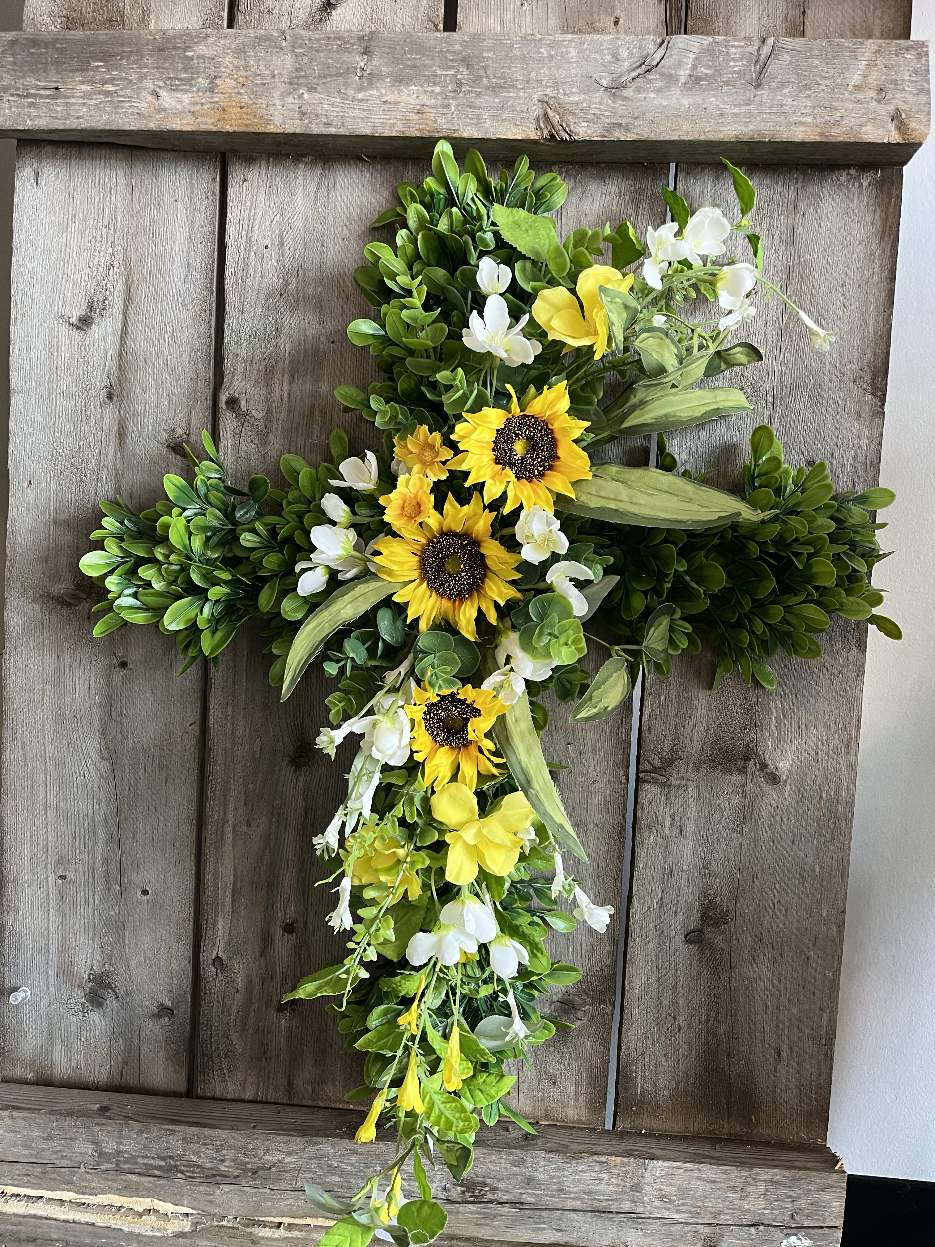 Cross-shaped floral arrangement with yellow sunflowers and white blossoms
