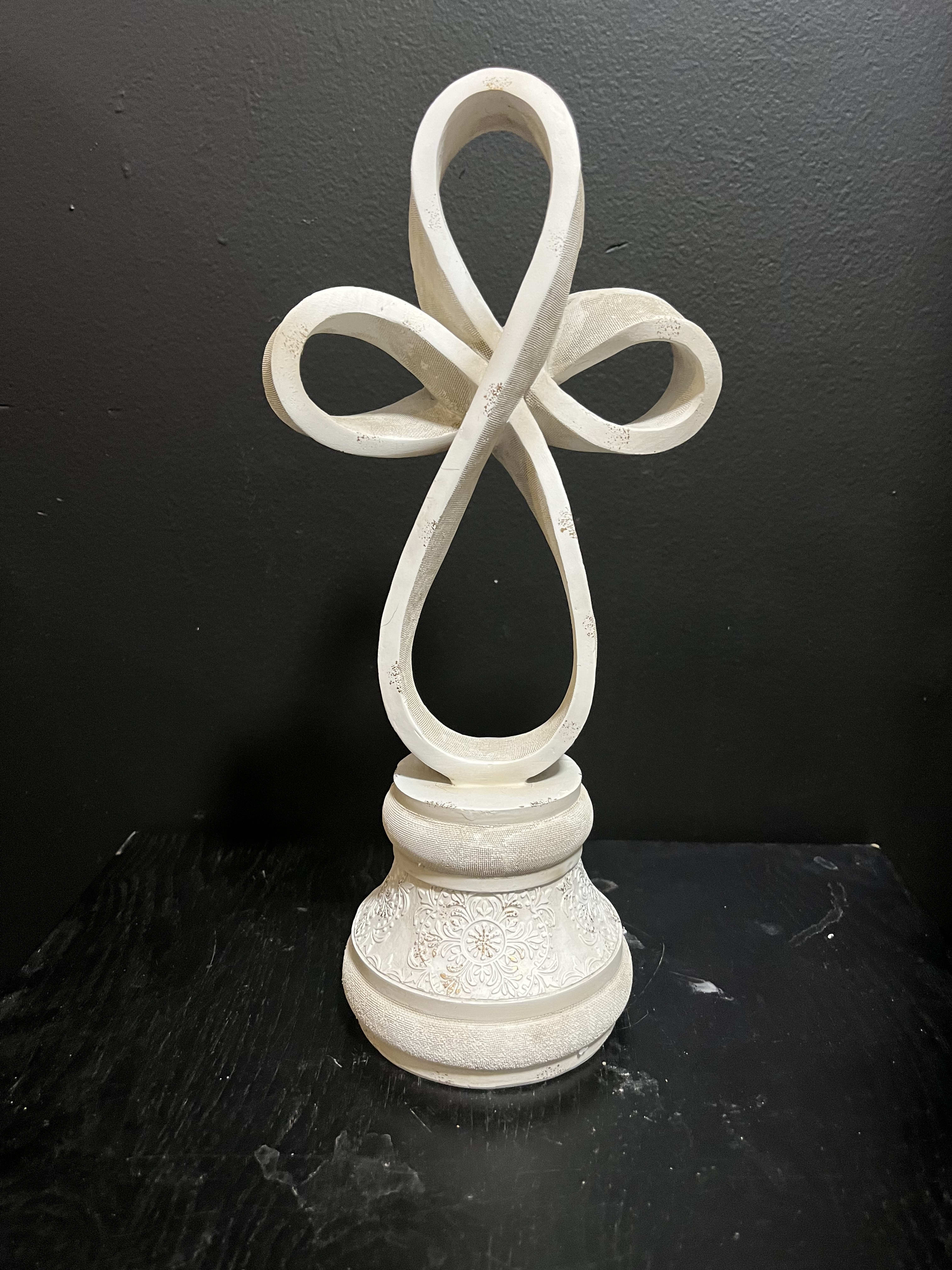 White decorative cross on a carved pedestal base
