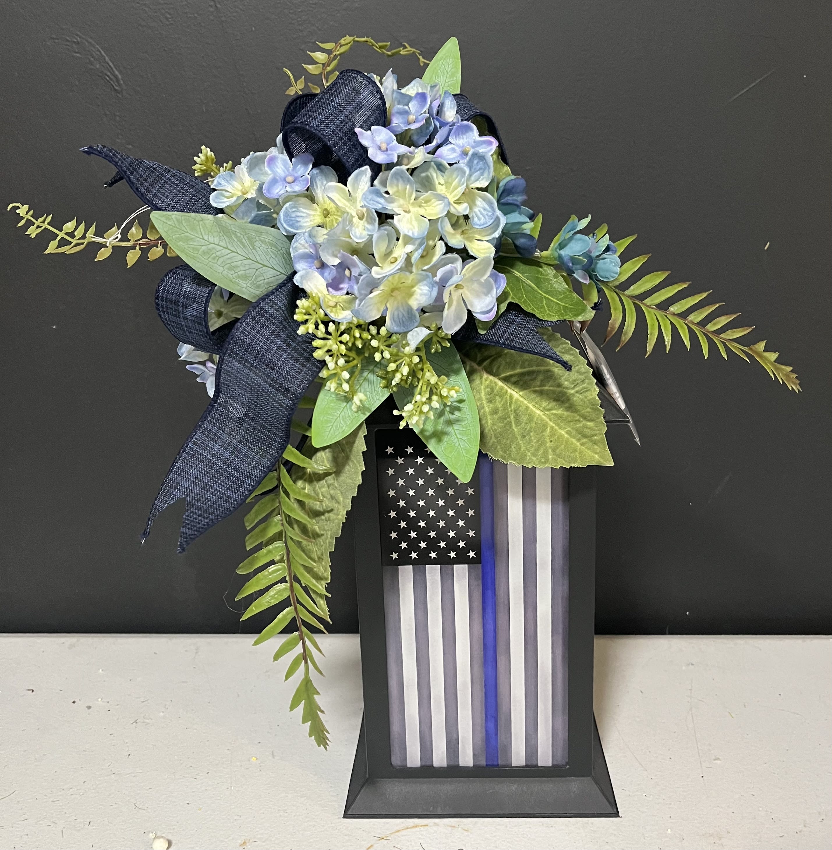 Blue hydrangea arrangement with a thin blue line flag plaque