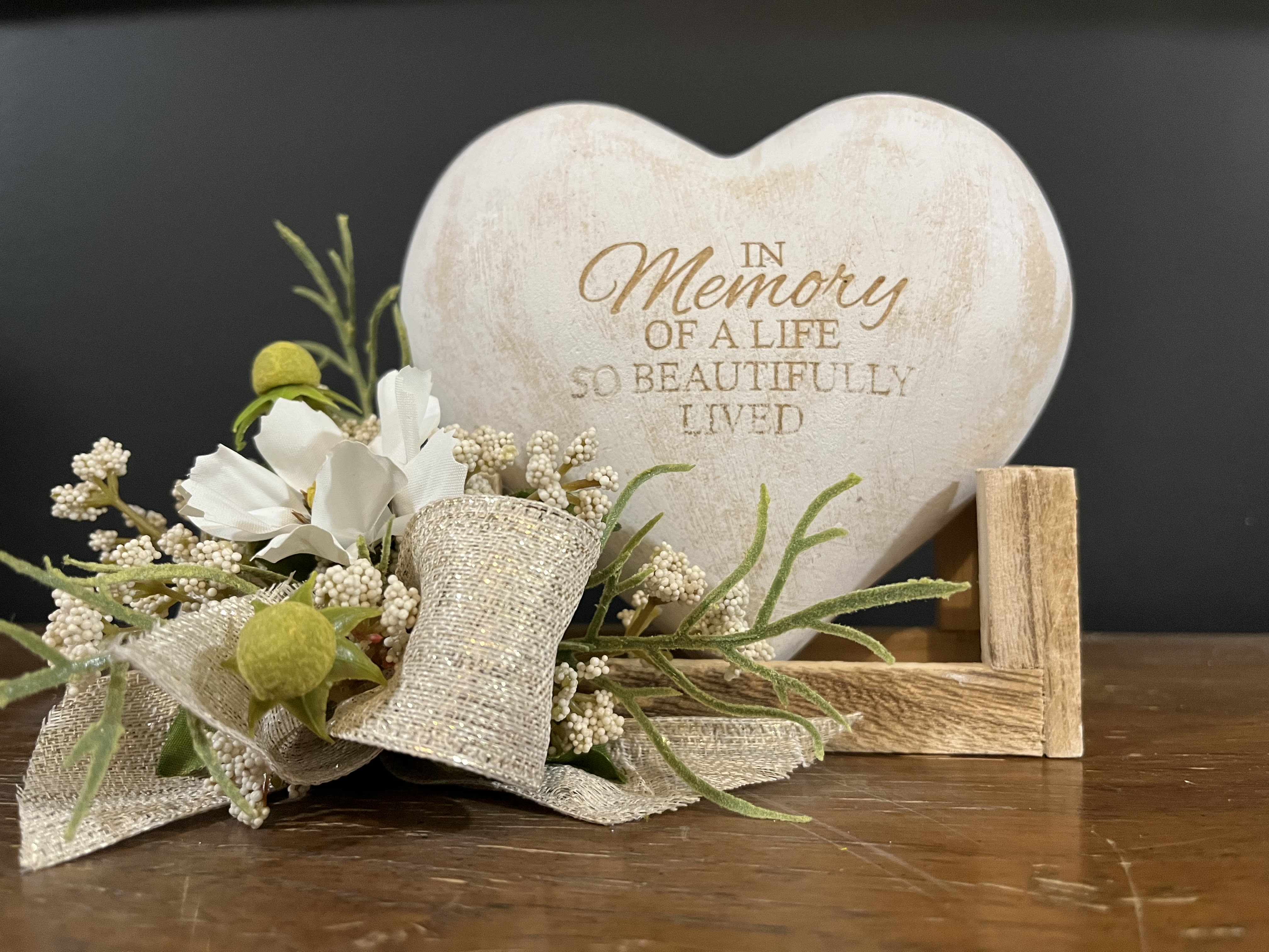 Heart-shaped memorial plaque with a small floral accent and ribbon