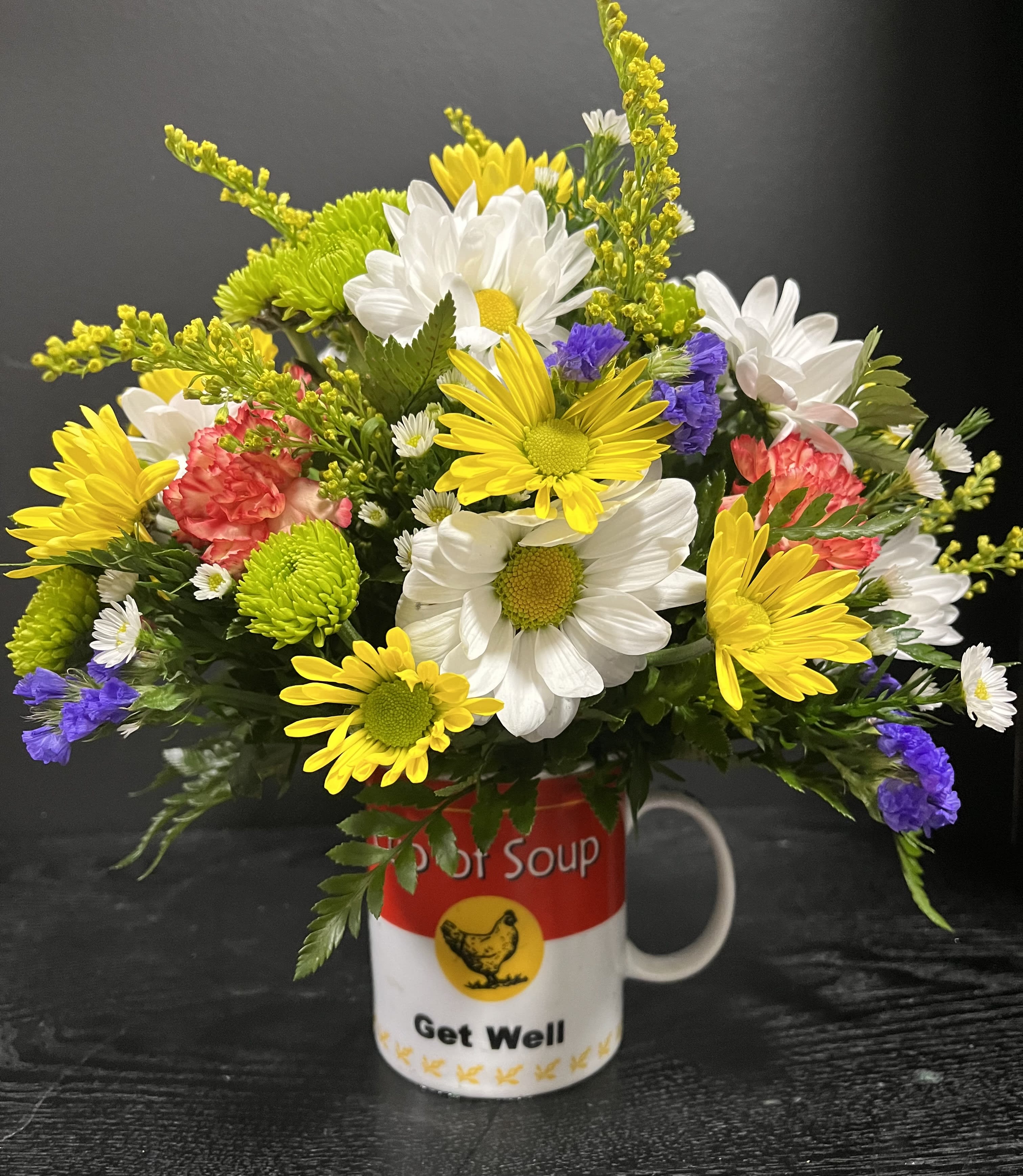 Mixed daisies and carnations arranged in a Get Well mug