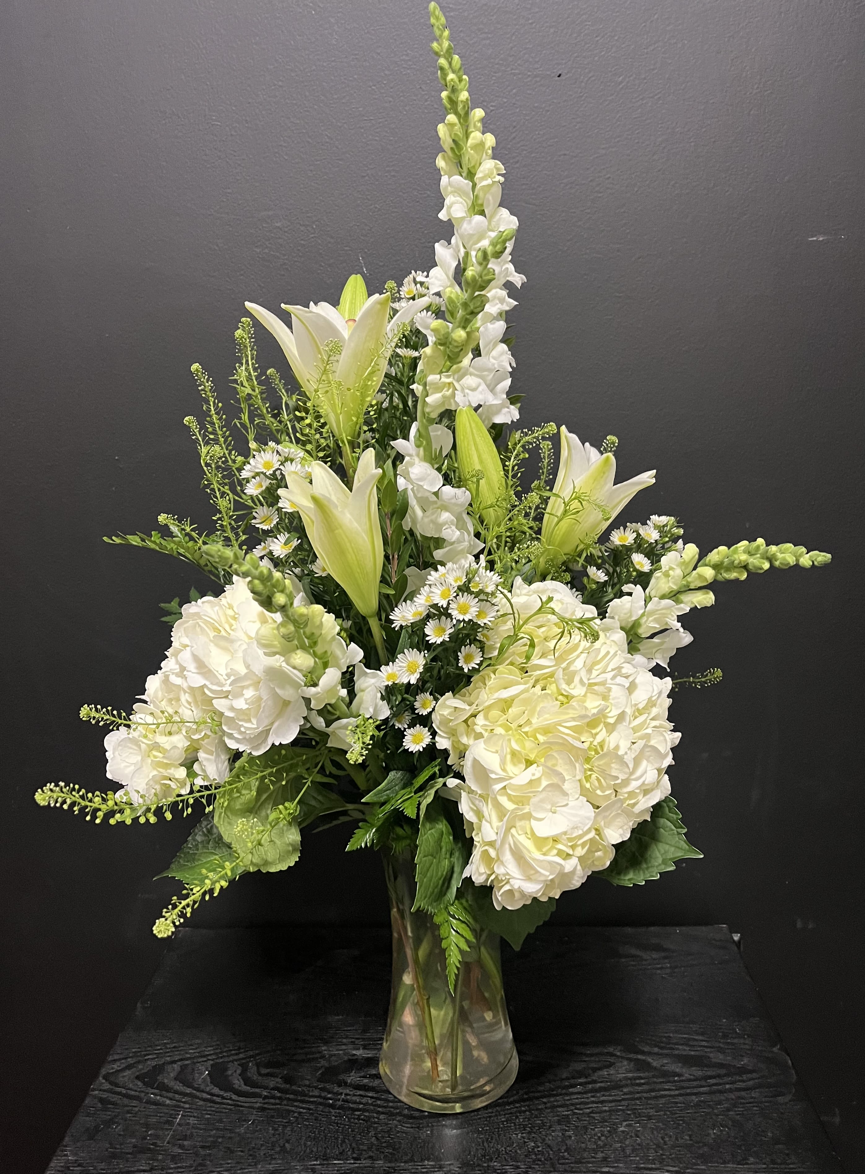 White lilies and hydrangeas arranged in a clear glass vase