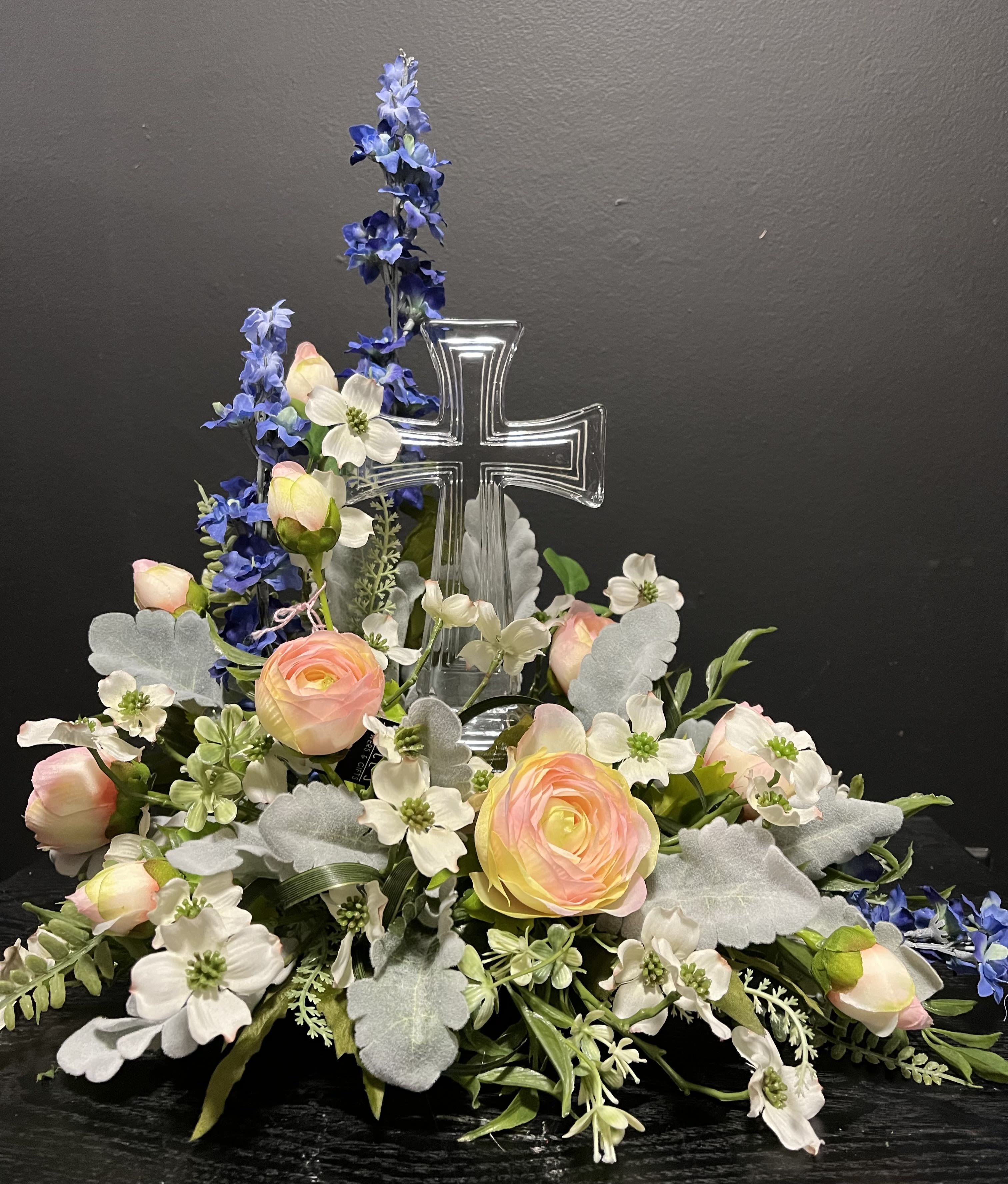 Floral arrangement with a clear cross centerpiece and pastel blooms