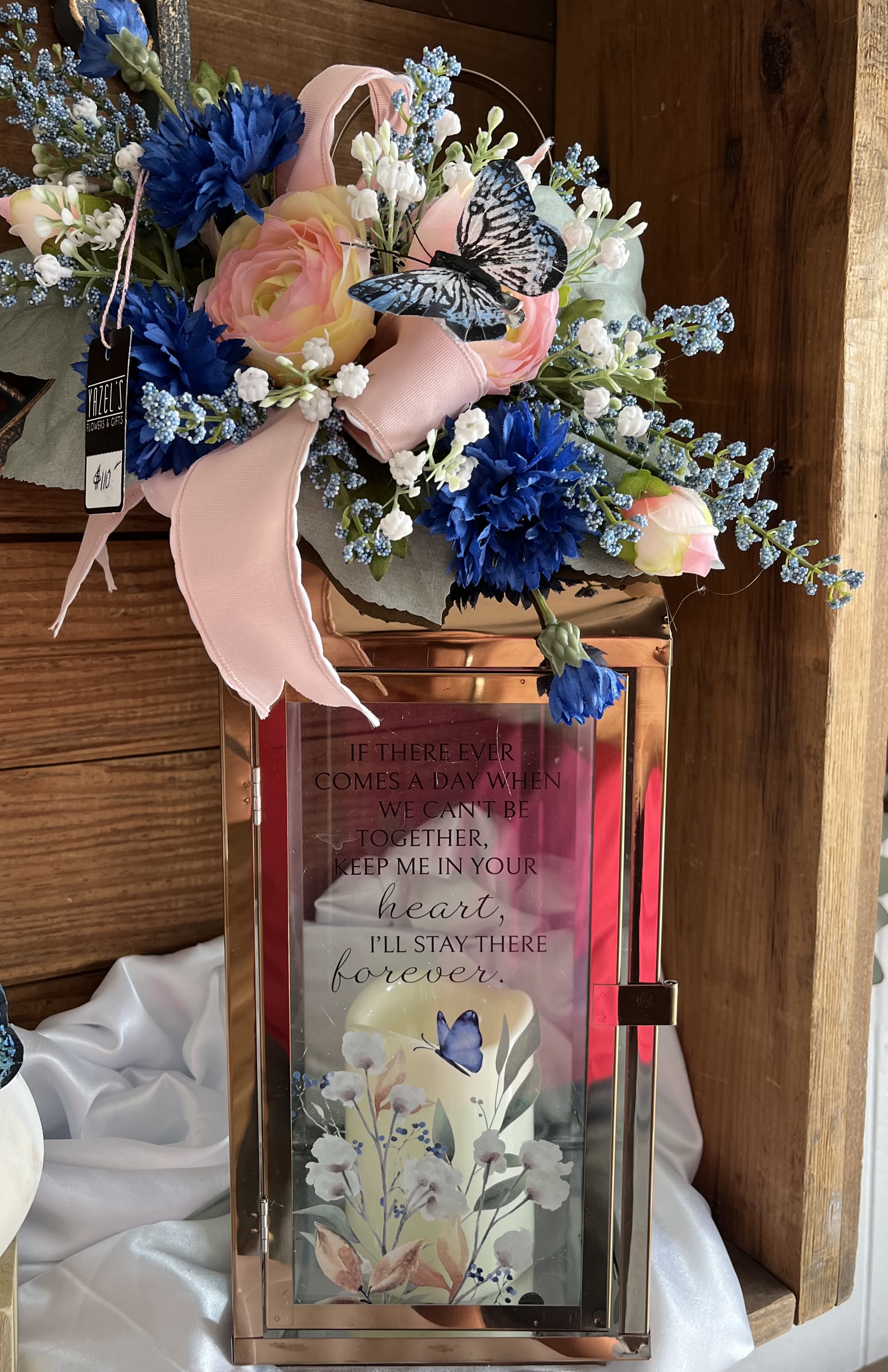 Pink and blue floral arrangement on a rose-gold lantern with a butterfly accent