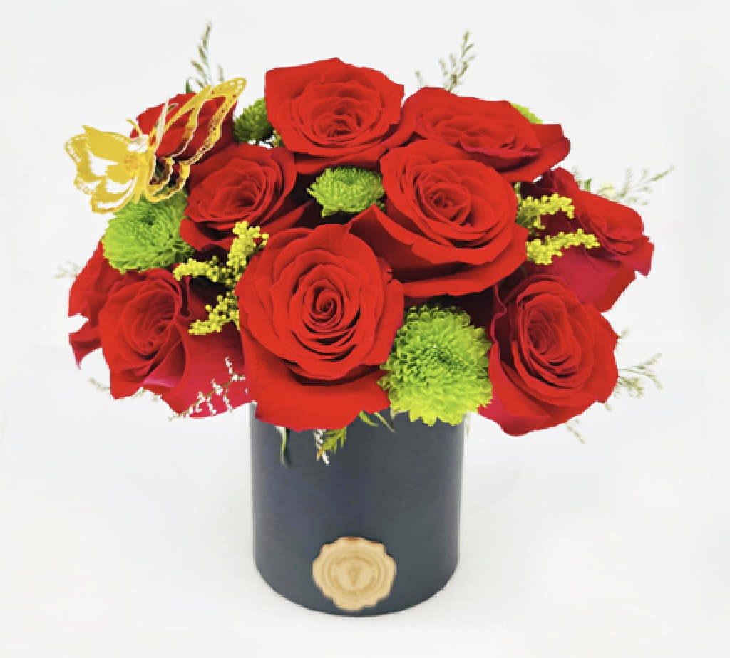 Red roses with green accents in a black cylindrical box