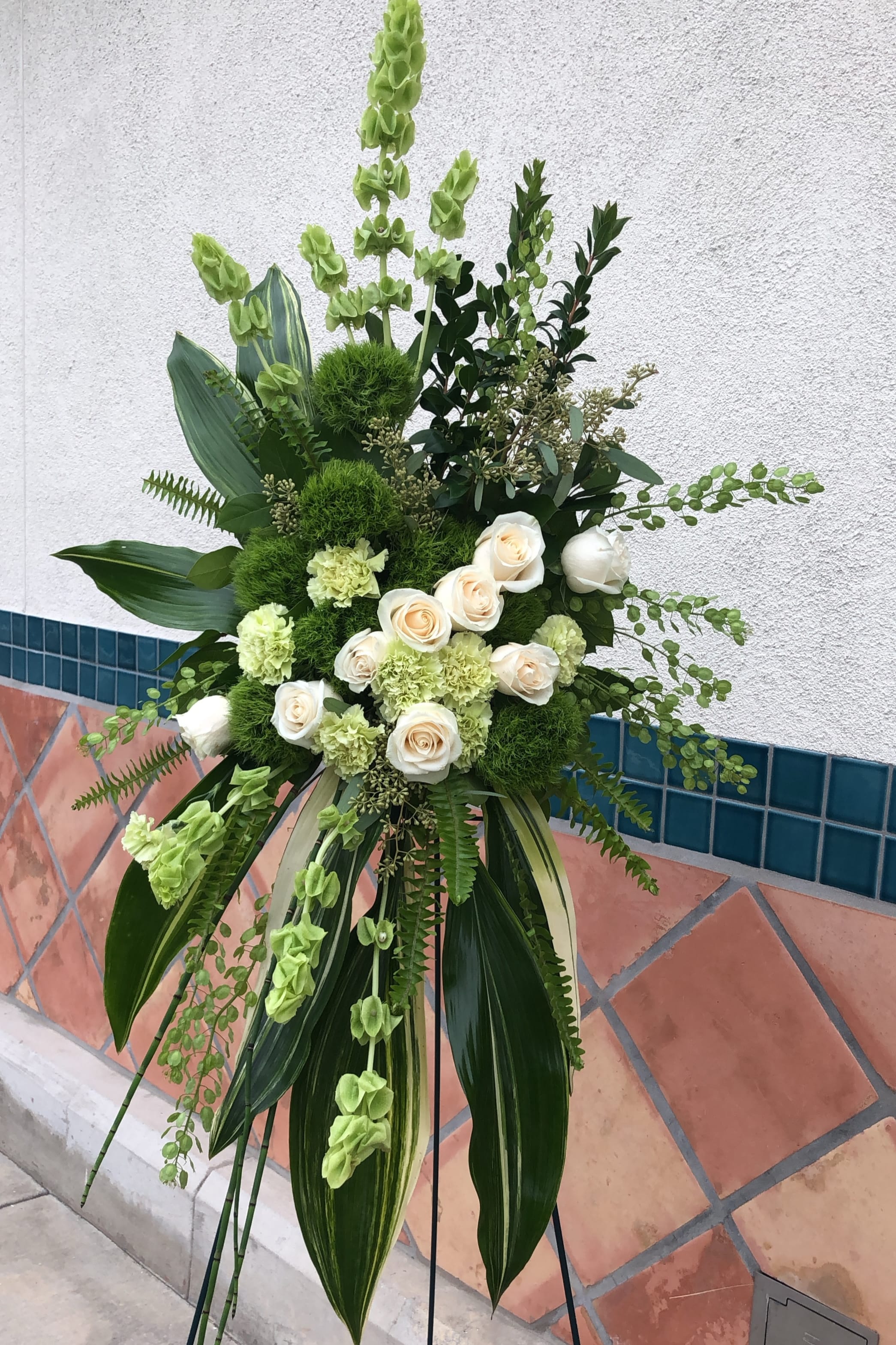 Tall green and white floral standing arrangement with roses and carnations