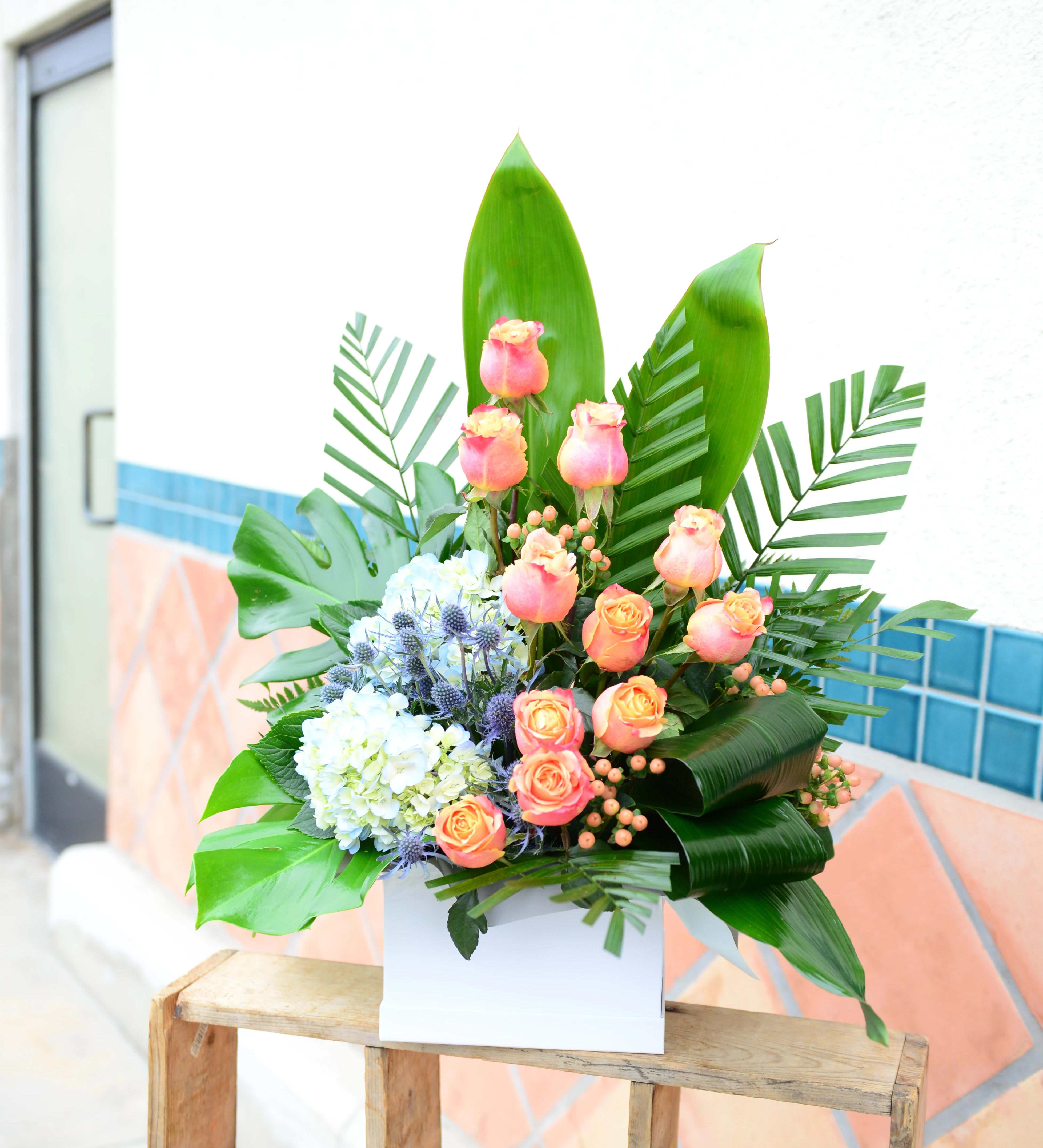 Tropical bouquet with pink roses and blue hydrangeas in a white box