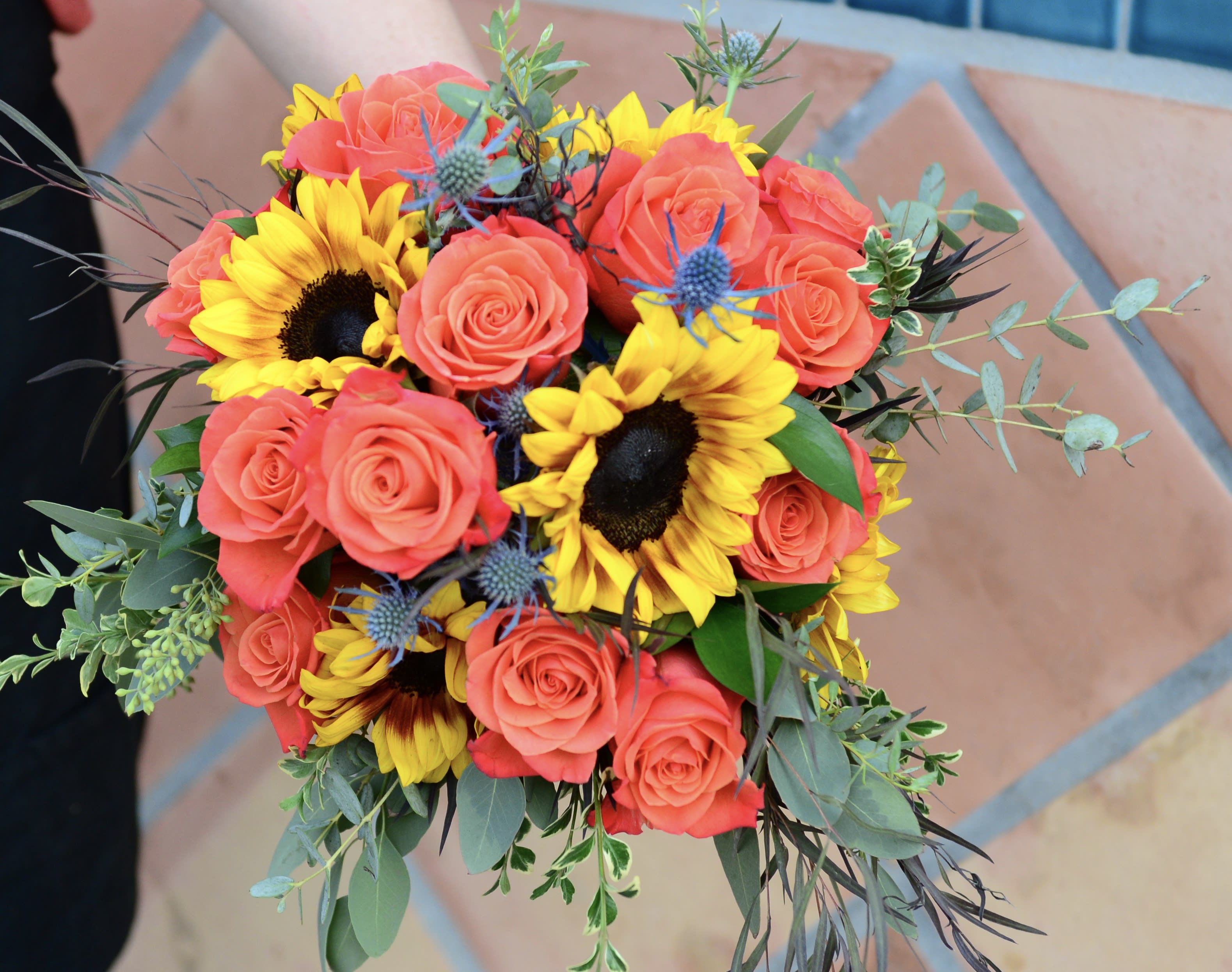 Bouquet of coral roses and yellow sunflowers with greenery